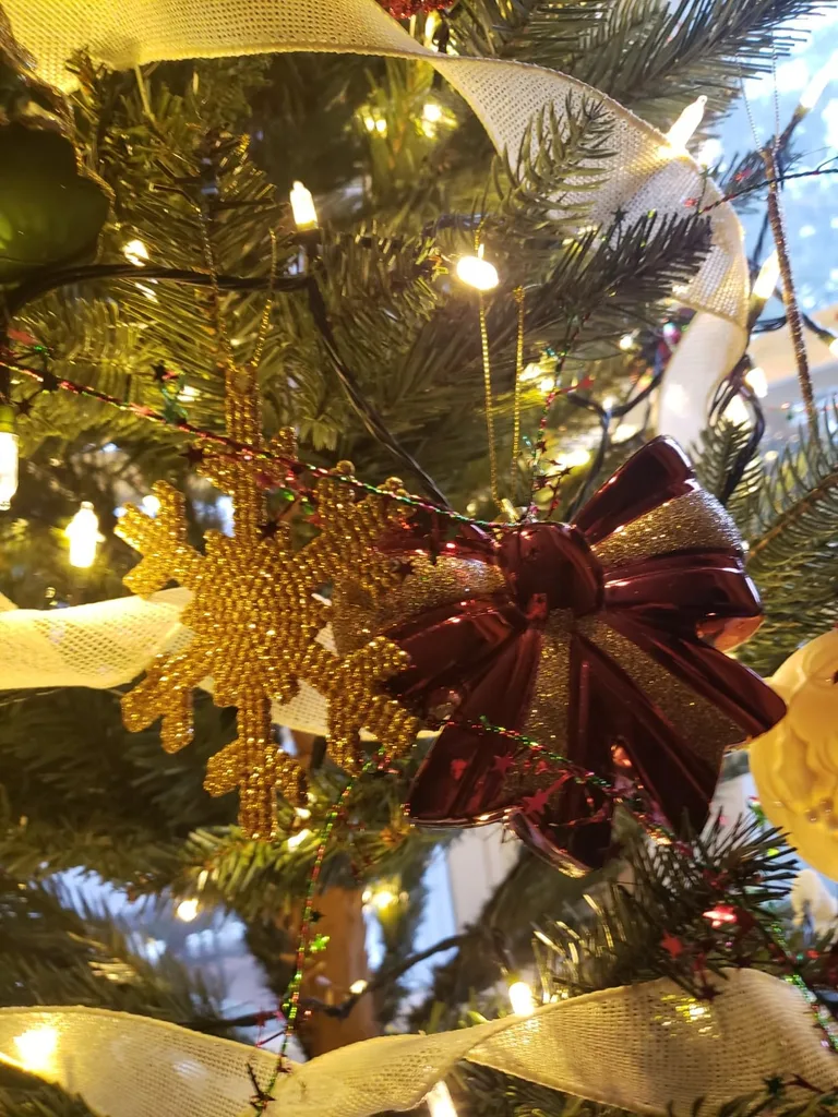 Beautiful Designer Christmas Decor Dupes You Can Buy or DIY – Gold Christmas Ornaments with Burgundy Bows

A Christmas tree is decorated with sparkling gold ornaments, warm string lights, and a large burgundy bow that adds a rich pop of color. The combination of metallic finishes and deep red accents creates a glamorous, traditional holiday look.