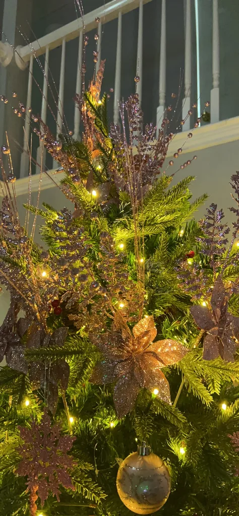 Beautiful Designer Christmas Decor Dupes You Can Buy or DIY – Tall Christmas Tree with Pink and Gold Ornaments

A tall Christmas tree stretches toward the ceiling, glowing with warm lights and decorated with pink, gold, and champagne-colored ornaments. Set beneath an indoor balcony, the tree creates a dramatic holiday centerpiece with a soft, elegant color palette and a festive glow.