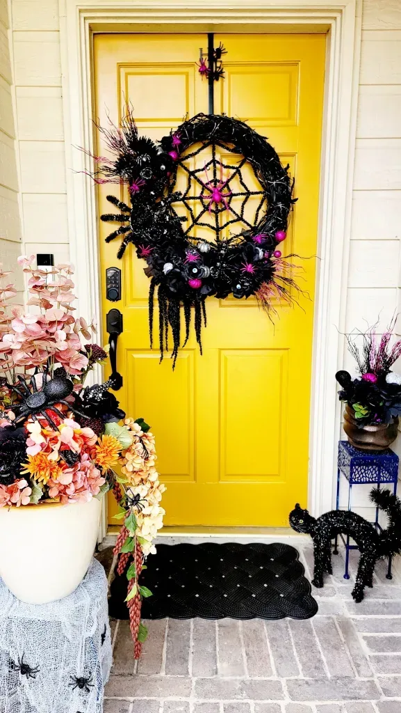 Fall in Love With This Gorgeous Fall-O-Ween Floral DIY - White ceramic planter overflowing with pink, orange, and red flowers, elevated on a decorative blue metal plant stand.