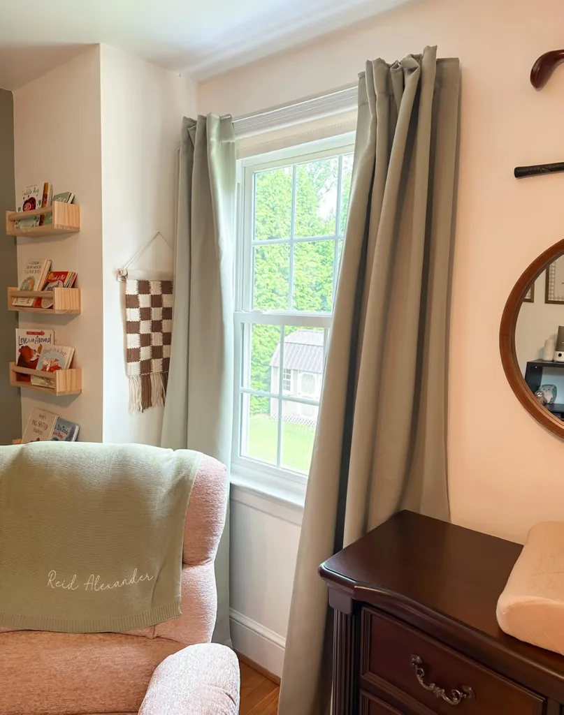 Refresh Your Living Room for Fall in 7 Easy Ways – Soft beige curtains frame a bright living room window beside a wooden side table and upholstered chair, creating a calm, comfortable space with warm neutral tones.