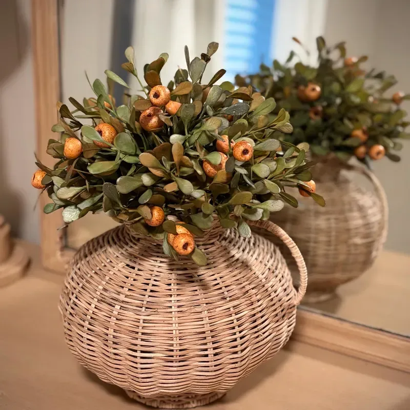 Refresh Your Living Room for Fall in 7 Easy Ways – A woven basket filled with autumn greenery, small orange berries, and decorative accents adds natural texture and a touch of fall color to a wooden living room table.
