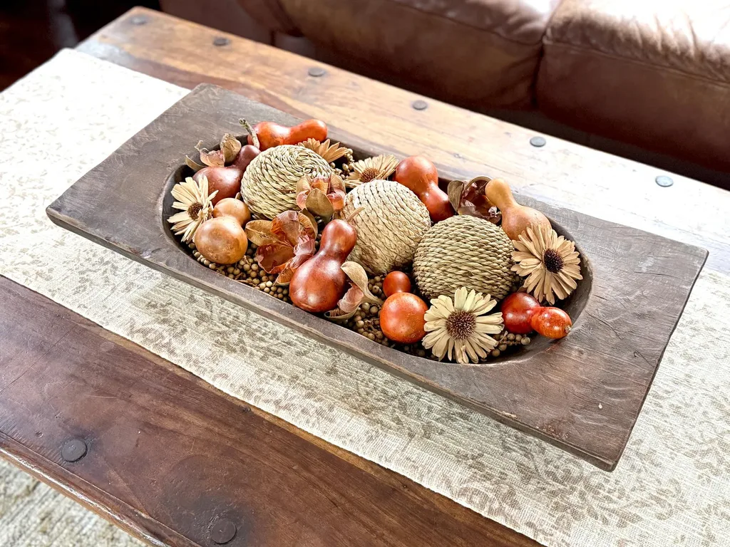 Refresh Your Living Room for Fall in 7 Easy Ways – A rustic wooden tray filled with mini pumpkins, pinecones, acorns, and other natural decorative elements creates a simple fall centerpiece for a coffee table.
