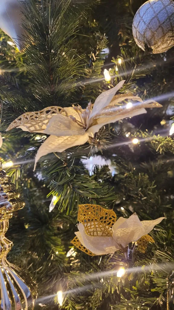 Beautiful Designer Christmas Decor Dupes You Can Buy or DIY – A close-up of a white and gold butterfly ornament nestled among evergreen branches and warm string lights showcases an elegant Christmas decoration with delicate details.